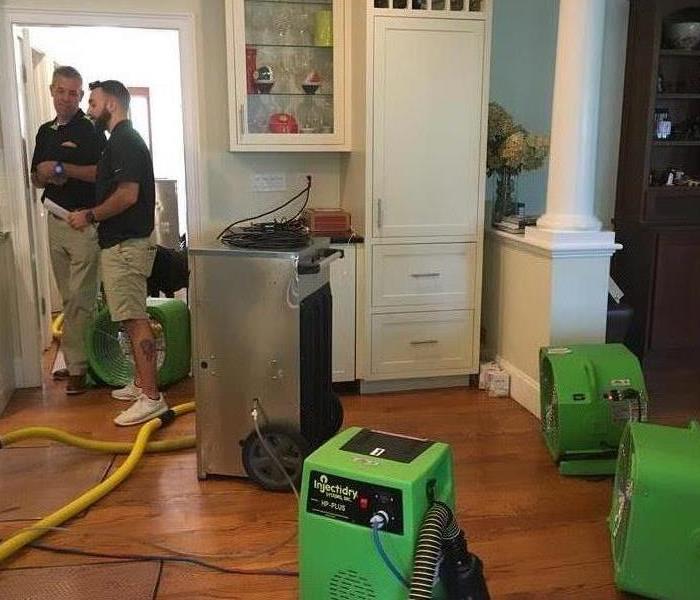 2 men standing in house with green equipment set out